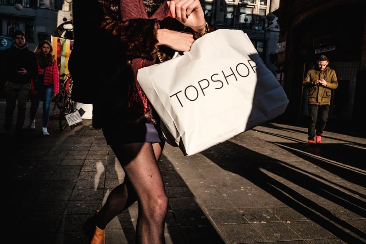 Photo of woman in black dress holding a Topshop bag