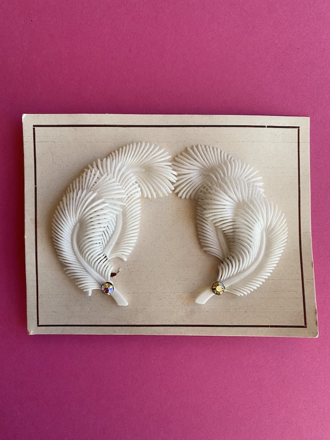 image showing a pair of deadstock vintage feather earrings on original card, in white
