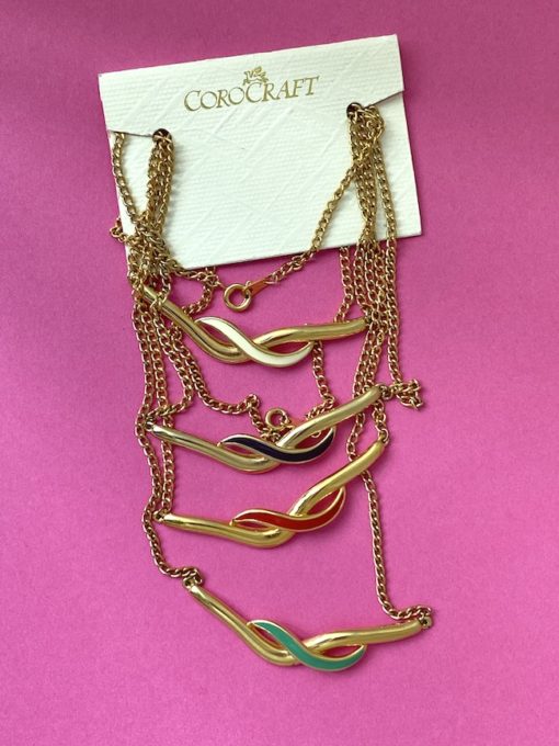image shows a selection of four Deadstock COROCRAFT Necklace in a wave shape on a pink background
