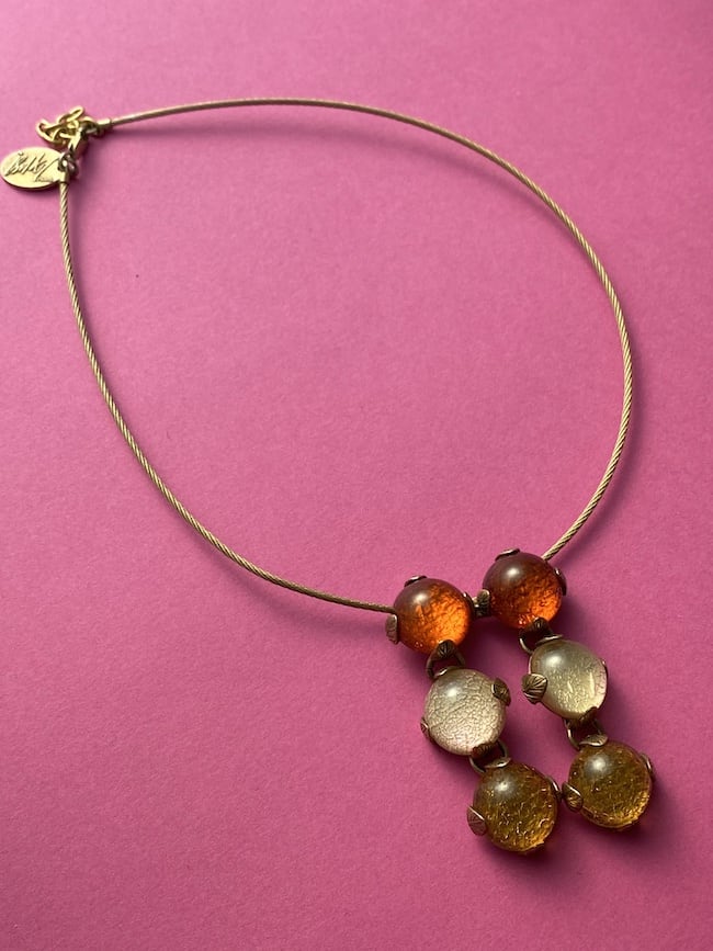 an image of a vintage necklace by ISAKY PARIS. This image features an orange resin pendant on a metal chain