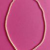 Image shows a Vintage Rosita Glass Pearl Necklace with clasp on a pink background