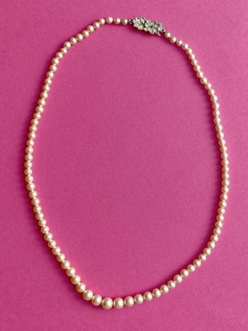 Image shows a Vintage Rosita Glass Pearl Necklace with clasp on a pink background