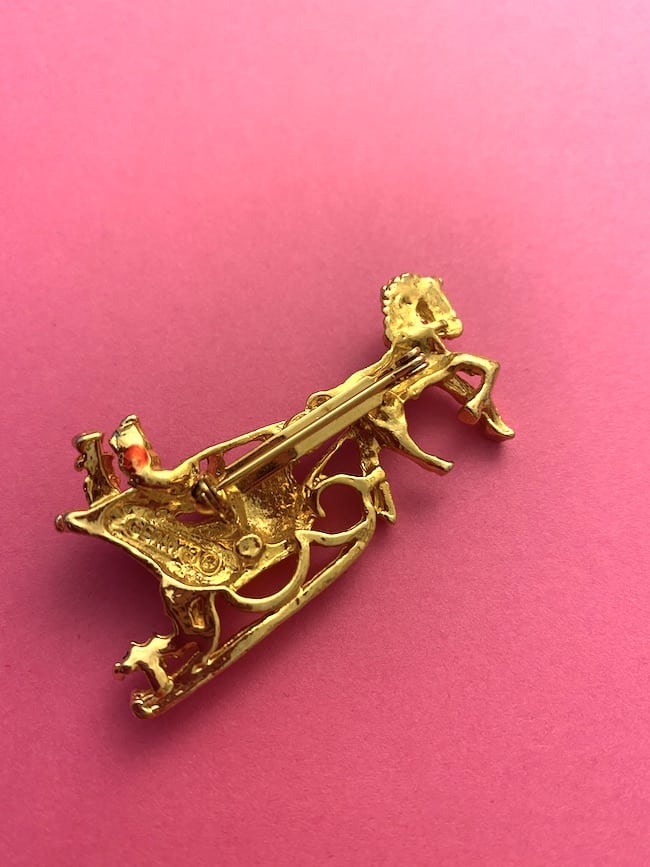 image of the back of a vintage brooch depicting a sleigh and horse