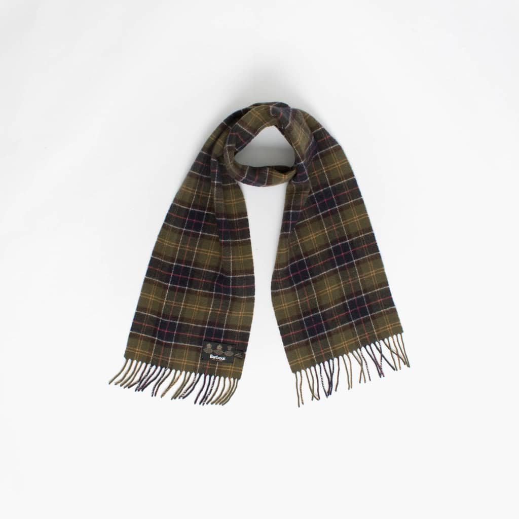 A dark tartan scarf with fringed ends is laid out against a plain white background