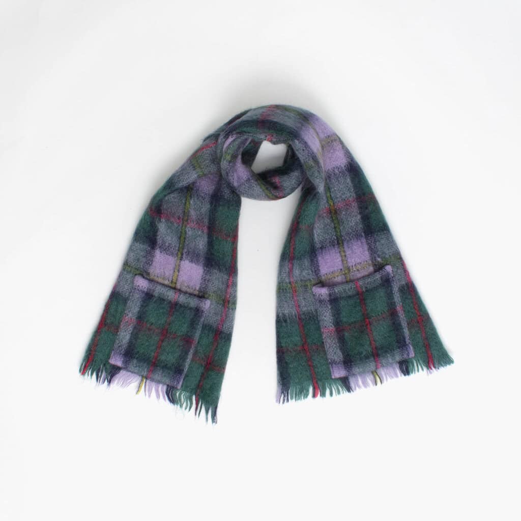 A plaid scarf with fringed ends is laid out against a plain white background.